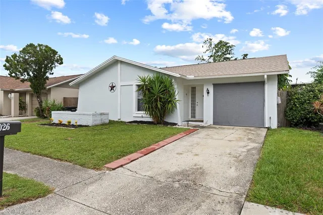 a view of a white house with a yard and potted plants