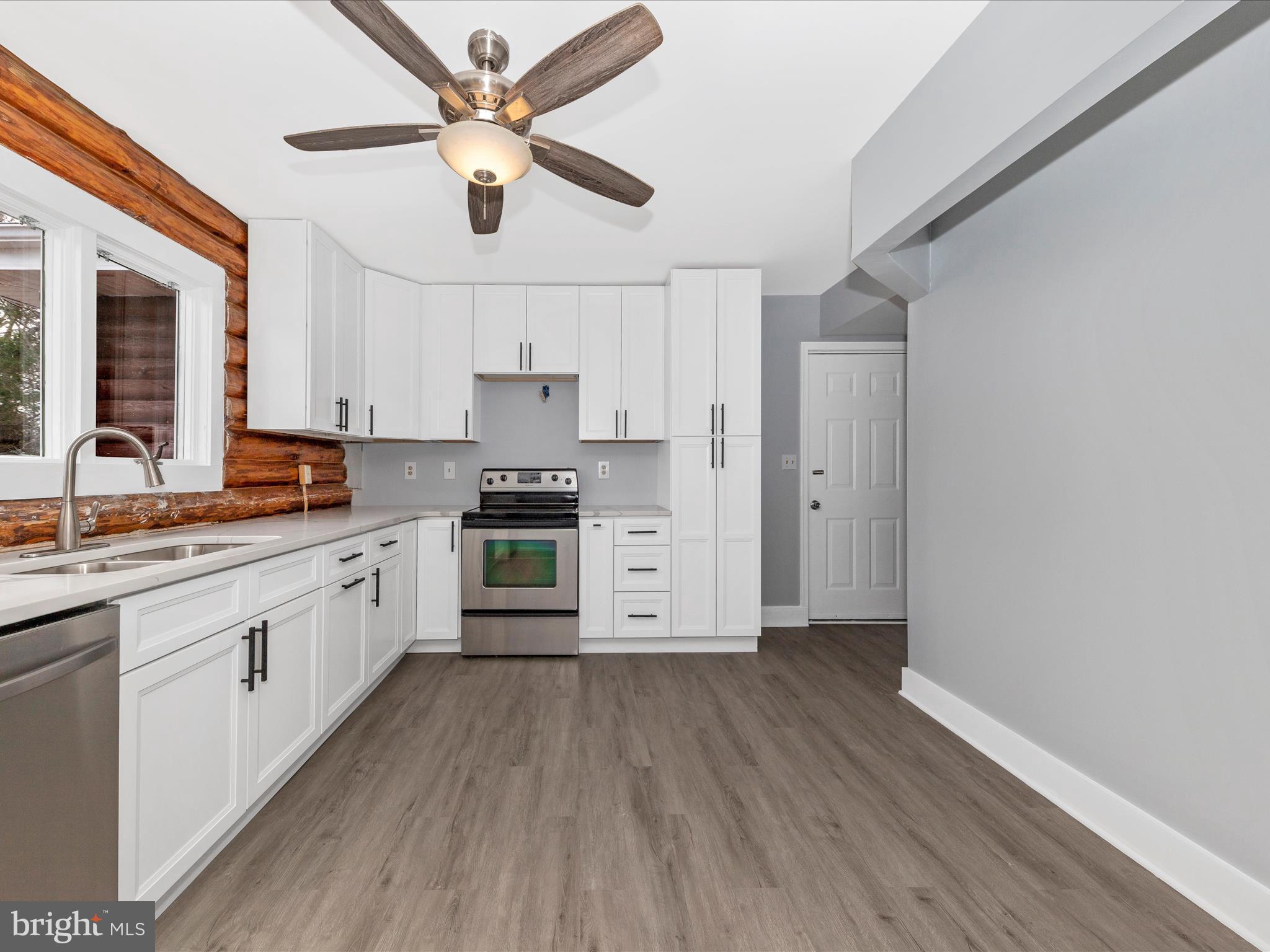 9513 Huntmaster Road Gaithersburg, MD 20882 - Photo 13 of 51 a kitchen with stainless steel appliances a stove a sink and white cabinets with wooden floor