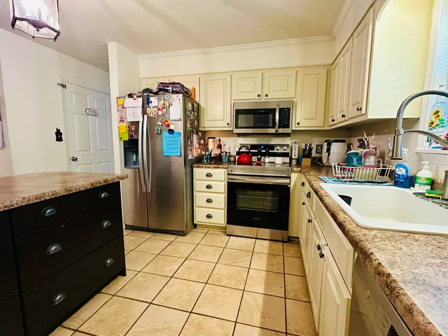 a kitchen with stainless steel appliances granite countertop a stove a refrigerator and a cabinets