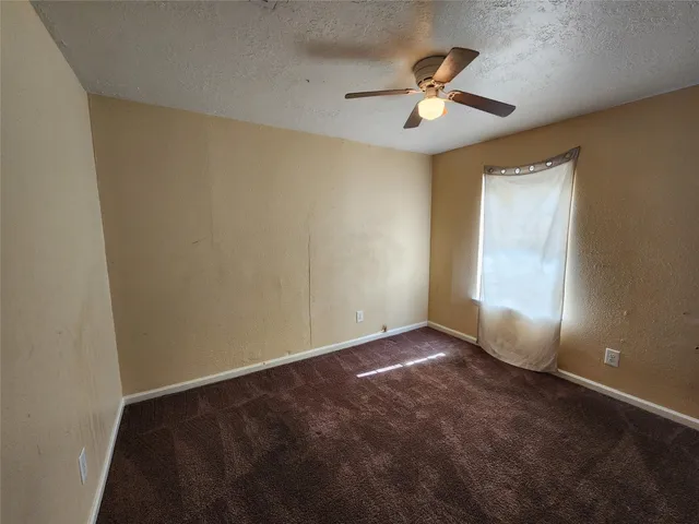 an empty room with ceiling fan and window