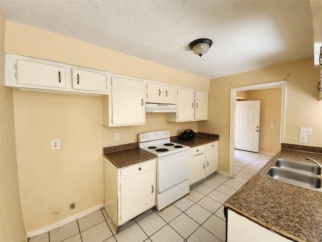 a kitchen with granite countertop a sink stove and cabinets