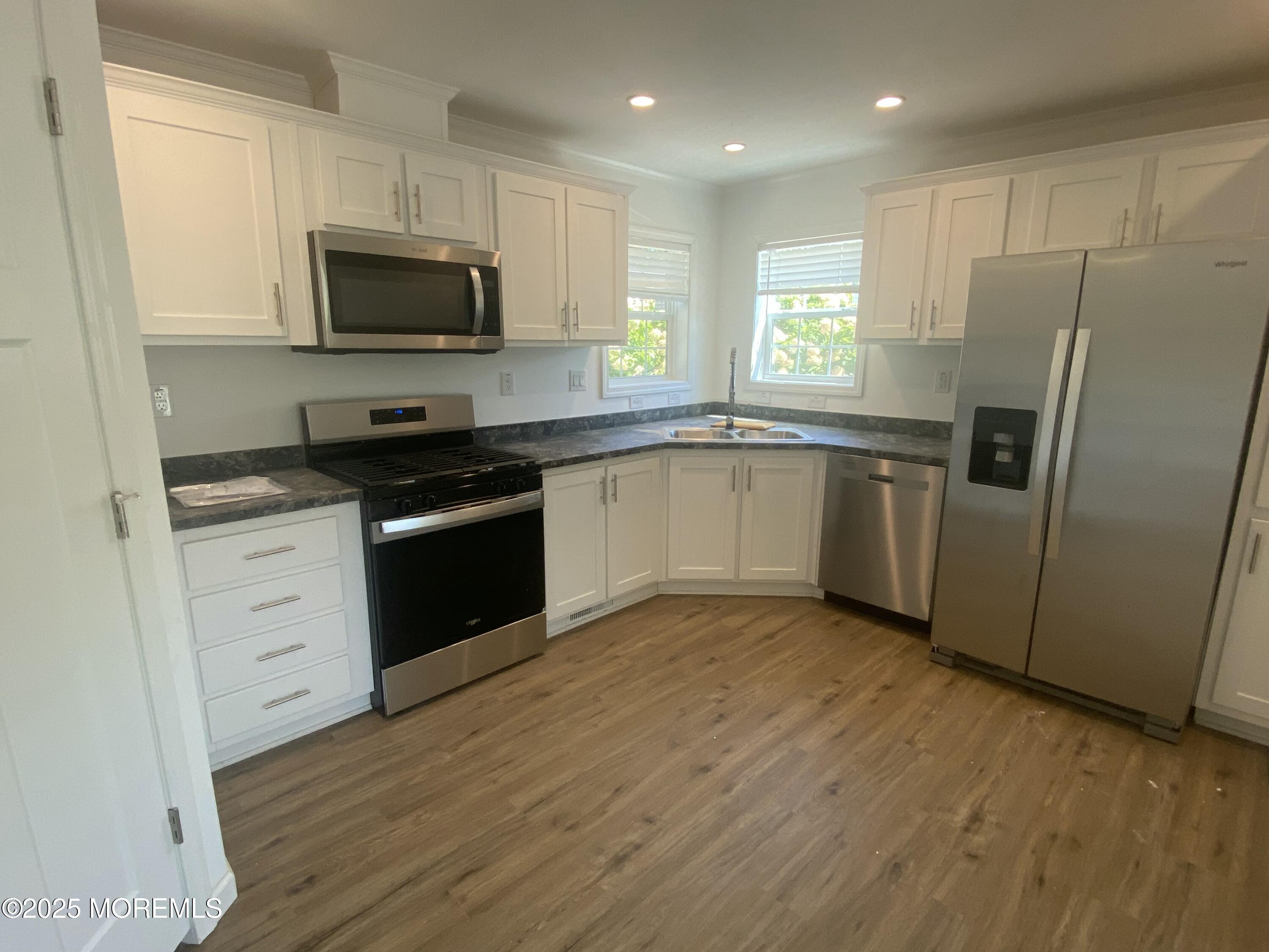 18 Maple Tree Court Manahawkin, NJ 08050 - Photo 2 of 21 a kitchen with granite countertop a refrigerator stove a sink and dishwasher with wooden floor