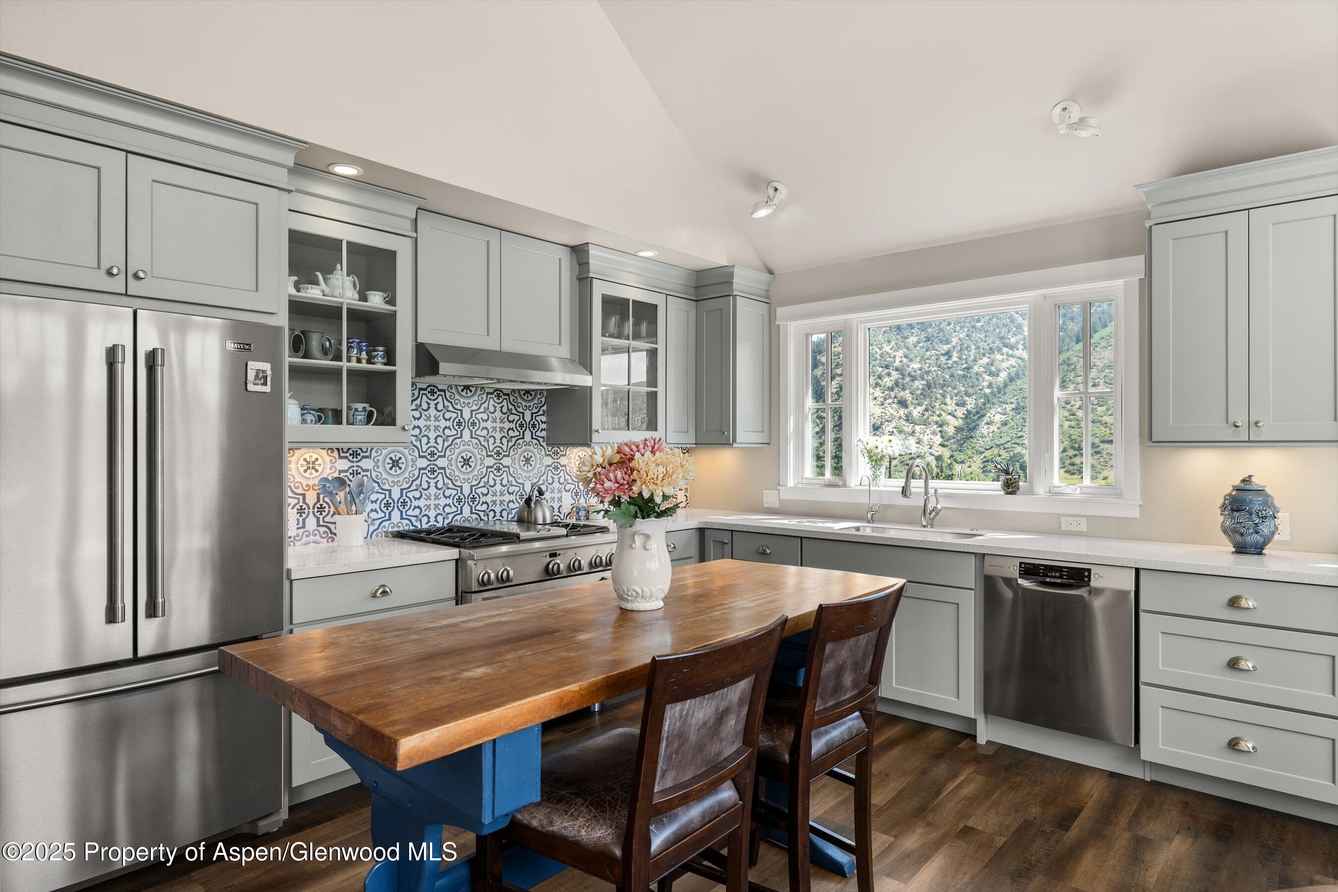 148 Gateway Road Snowmass, CO 81654 - Photo 5 of 32 a kitchen with stainless steel appliances granite countertop a stove a refrigerator a sink a dining table and chairs