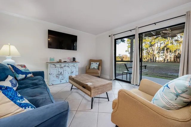 a living room with furniture floor to ceiling window hardwood floor and a flat screen tv