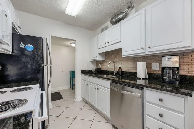 a kitchen with granite countertop a sink a stove and cabinets