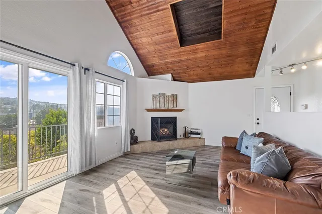 a living room with furniture a fireplace and floor to ceiling windows