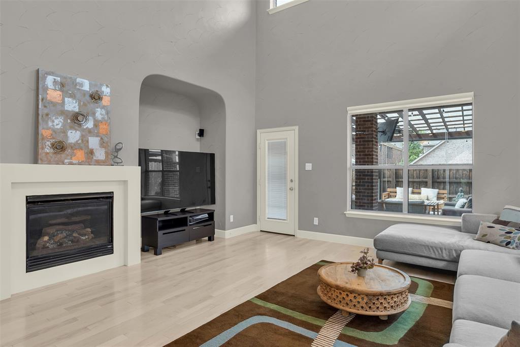 8631 Lohr Valley Road Irving, TX 75063 - Photo 10 of 32 Living area with light wood-style floors, a glass covered fireplace, and a high ceiling