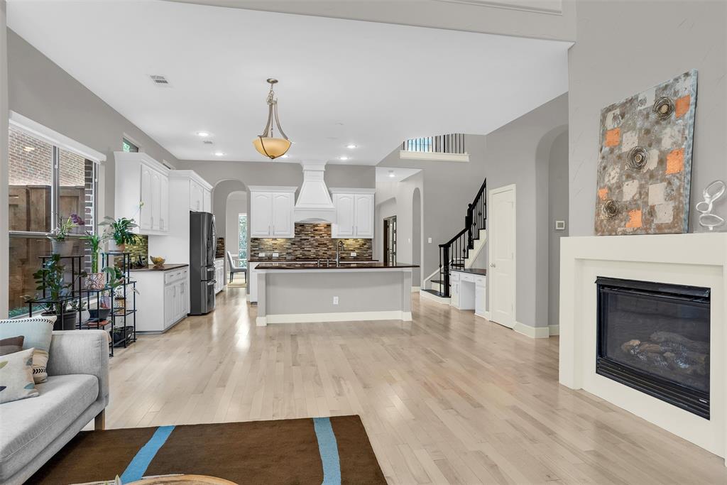 8631 Lohr Valley Road Irving, TX 75063 - Photo 12 of 32 Living area with arched walkways, a glass covered fireplace, and light wood-type flooring