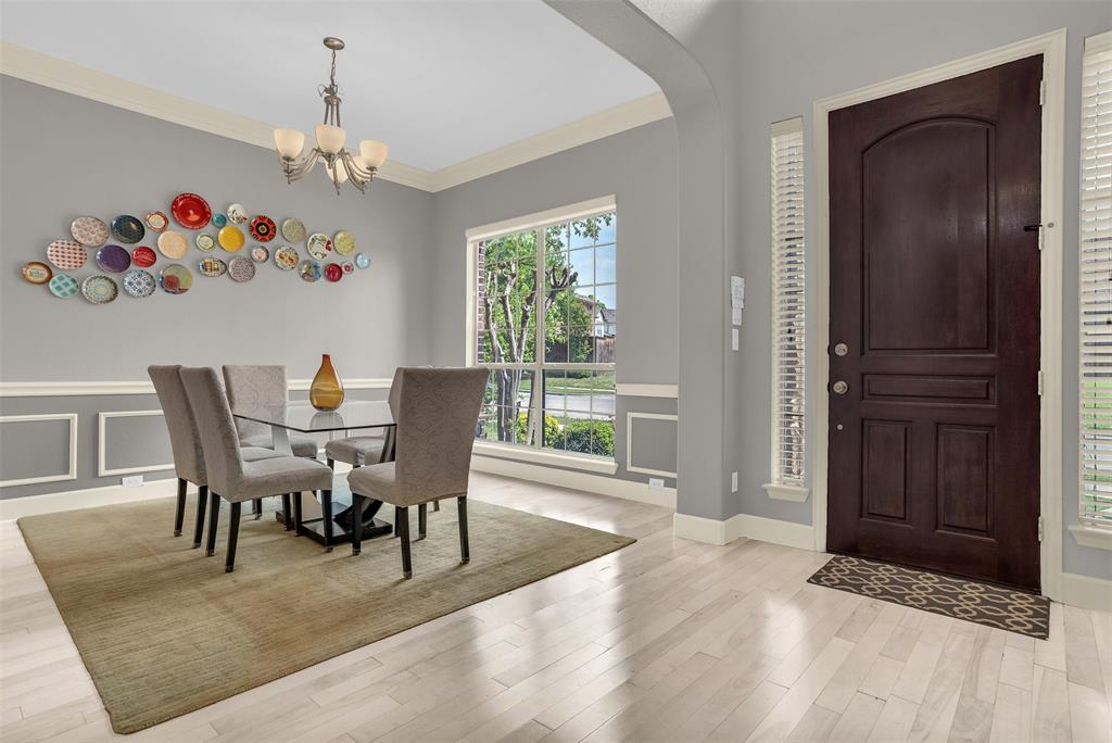 8631 Lohr Valley Road Irving, TX 75063 - Photo 5 of 32 Dining room featuring crown molding, suspended lighting, light wood-style flooring, arched walkways, and a decorative wall