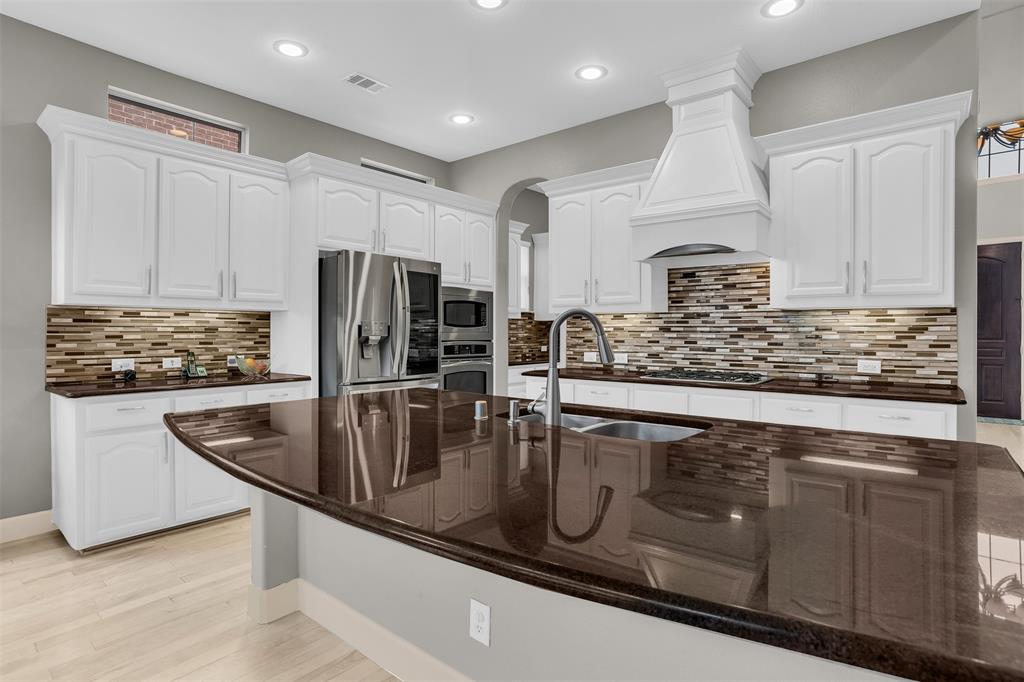 8631 Lohr Valley Road Irving, TX 75063 - Photo 6 of 32 Kitchen featuring stainless steel appliances, white cabinetry, dark stone counters, a spacious island, and decorative backsplash