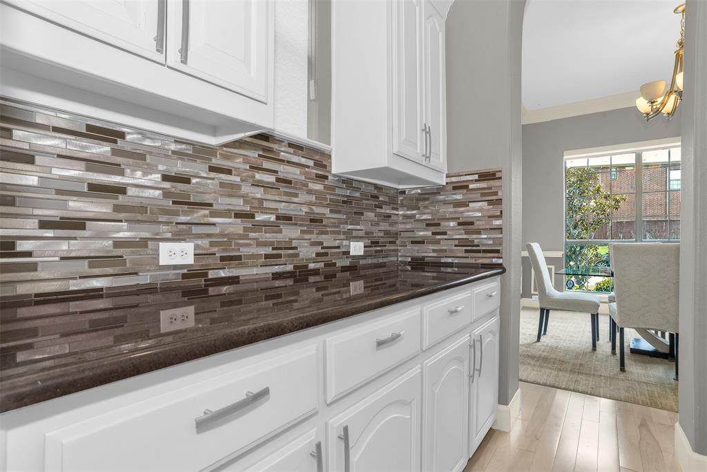 8631 Lohr Valley Road Irving, TX 75063 - Photo 8 of 32 Kitchen with dark stone counters, white cabinetry, light wood-type flooring, ornamental molding, and backsplash