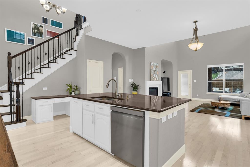 8631 Lohr Valley Road Irving, TX 75063 - Photo 31 of 32 Kitchen with a high ceiling, stainless steel dishwasher, open floor plan, an island with sink, and light wood-style floors