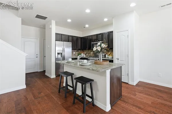 a kitchen with kitchen island a stove a refrigerator and a dining table with wooden floor