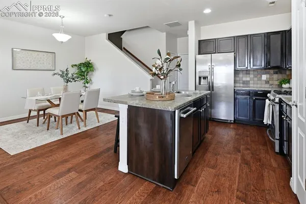 a kitchen with stainless steel appliances a dining table chairs stove and refrigerator