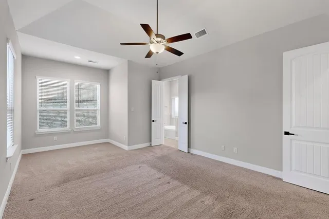 a view of an empty room with a ceiling fan and window