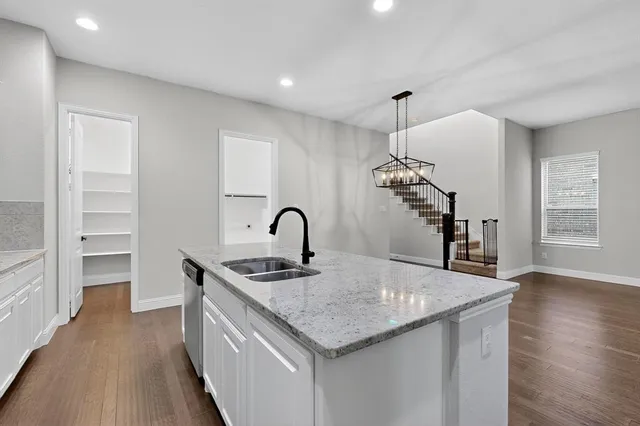 a kitchen with stainless steel appliances granite countertop a sink dishwasher and a stove with wooden floor