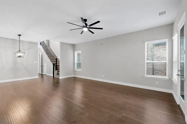 a view of an empty room with a window and wooden floor