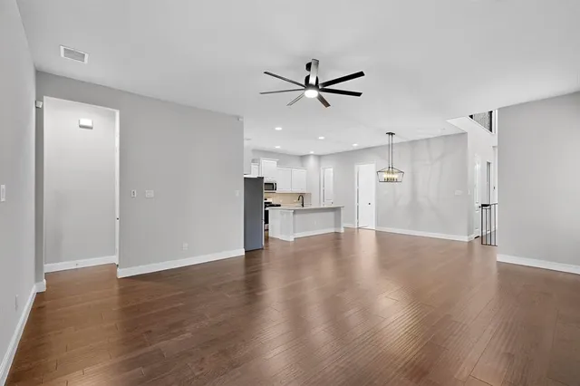 a view of an empty room with a window and wooden floor