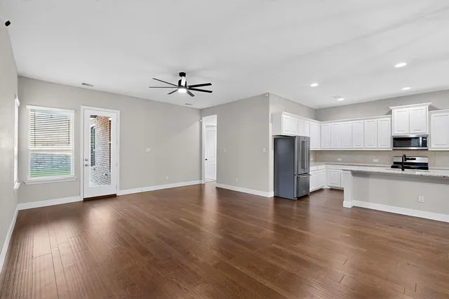 a view of kitchen with refrigerator stove and wooden floor
