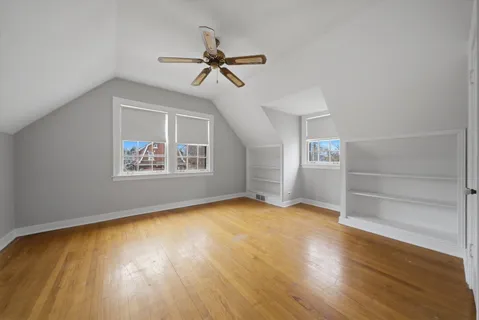 a view of empty room with wooden floor and fan