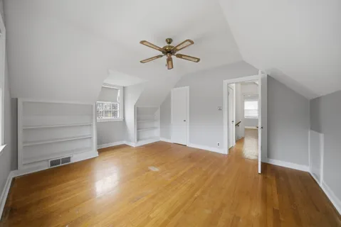 a view of empty room with wooden floor and fan