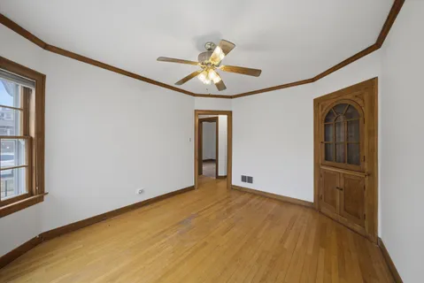 a view of empty room with wooden floor and fan
