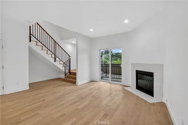 a view of an empty room with wooden floor fireplace and a window