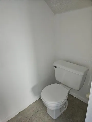 a white toilet sitting next to a white wall