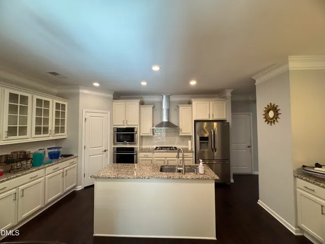 a large kitchen with kitchen island a large counter top stainless steel appliances and cabinets