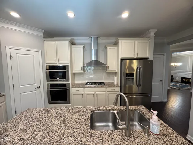 a kitchen with stainless steel appliances granite countertop a refrigerator sink and stove