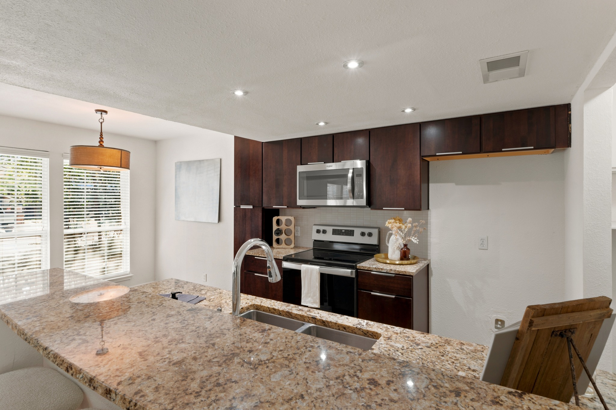 1504 Allen Road, Unit B Austin, TX 78746 - Photo 12 of 24 Rich dark wood cabinetry contrasts beautifully with granite countertops in this open kitchen layout.
