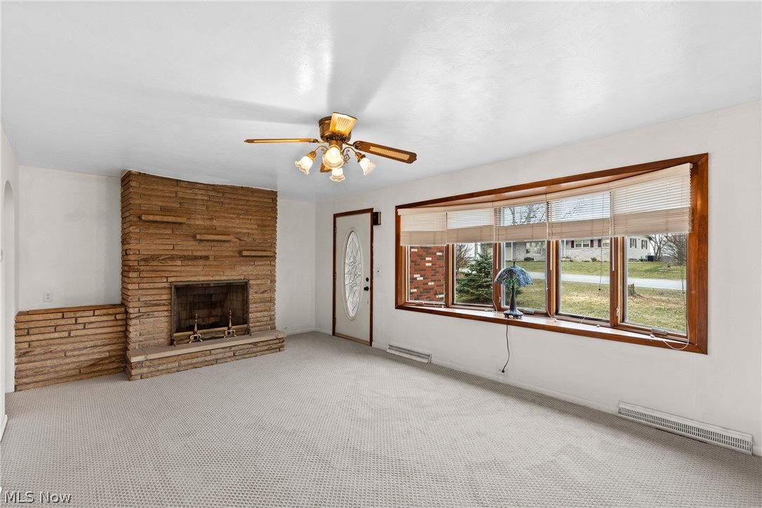 70828 Crescent Road St. Clairsville, OH 43950 - Photo 5 of 40 Unfurnished living room with ceiling fan, a stone fireplace, light carpet, and baseboard heating