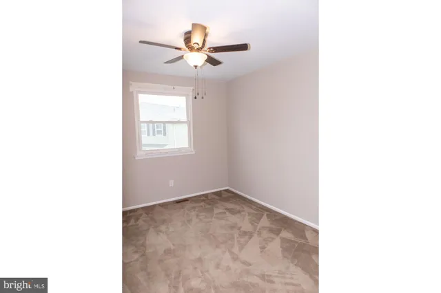 an empty room with a window and a fan