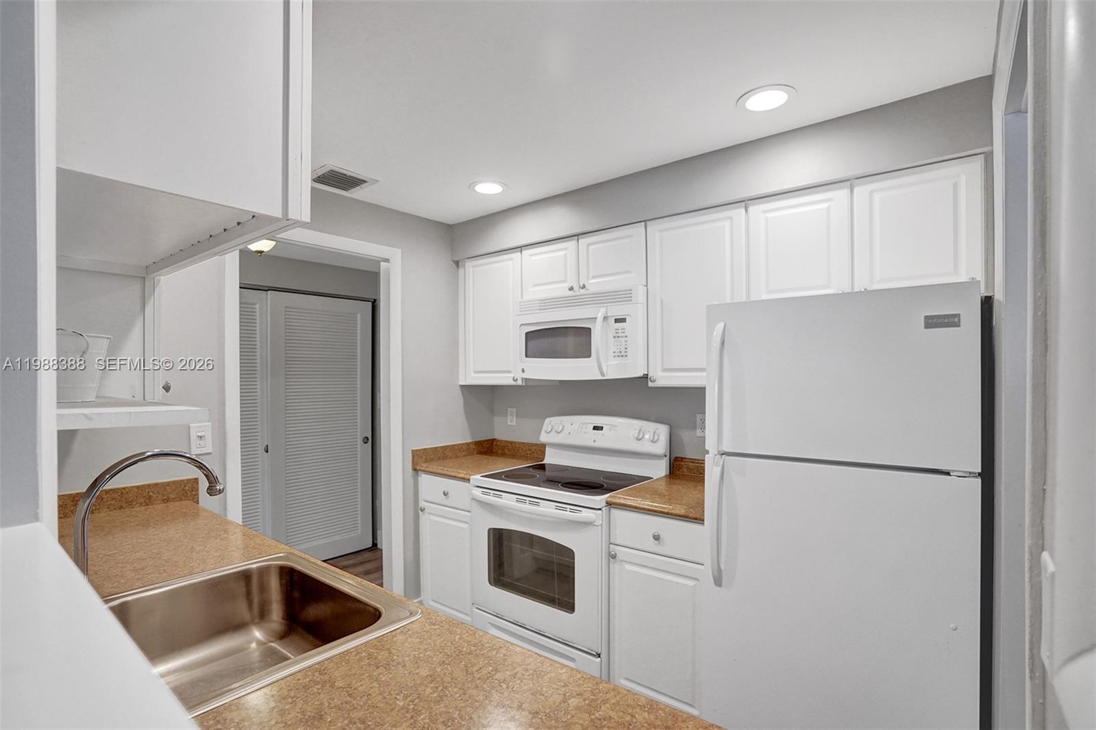 400 North Riverside Drive, Unit 214 Pompano Beach, FL 33062 - Photo 3 of 67 a kitchen with stainless steel appliances granite countertop a refrigerator a stove a sink and a white cabinets with wooden floor