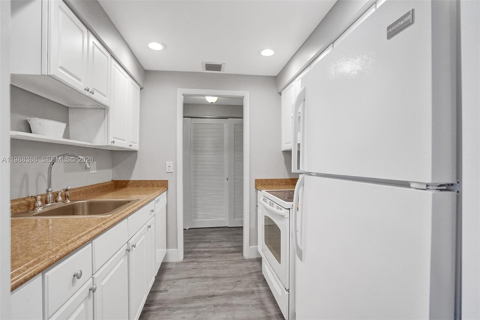 400 North Riverside Drive, Unit 214 Pompano Beach, FL 33062 - Photo 4 of 67 a kitchen with a sink a refrigerator and cabinets