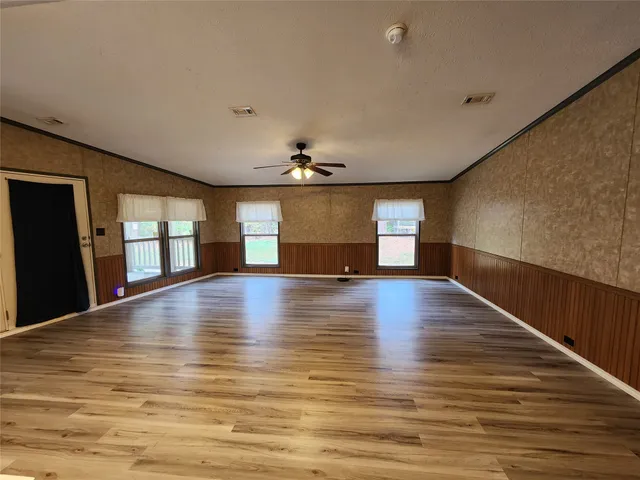 a view of empty room with wooden floor and fan