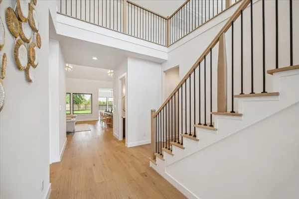 a view of staircase with lots of frames on wall and wooden floor