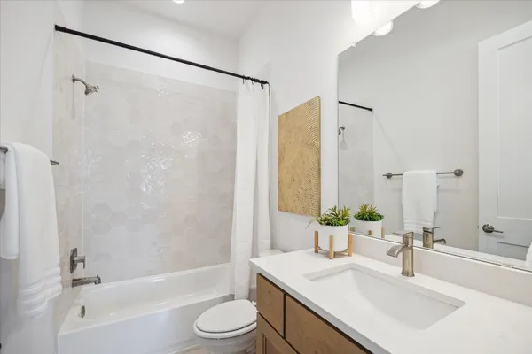 a bathroom with a granite countertop bathtub shower sink vanity mirror and toilet