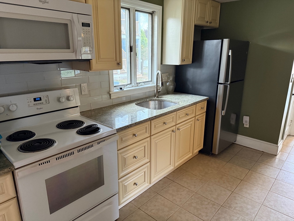 128 Boston Street, Unit 4 Salem, MA 01970 - Photo 5 of 17 a kitchen with a refrigerator sink and cabinets