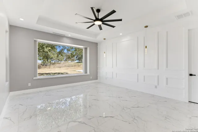 an empty room that has a window and a ceiling fan in it