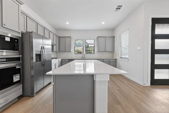 a kitchen with stainless steel appliances granite countertop a refrigerator a sink dishwasher a stove and a refrigerator