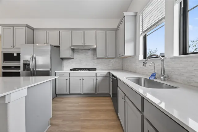 a kitchen with granite countertop a sink stainless steel appliances and cabinets