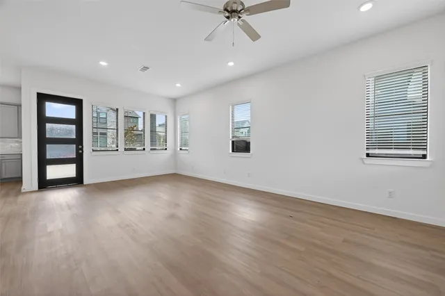 a view of an empty room with a window and wooden floor