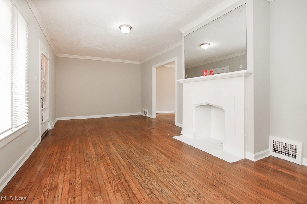 3973 Navahoe Road Cleveland, OH 44121 - Photo 4 of 14 Unfurnished living room with visible vents, crown molding, baseboards, and hardwood / wood-style flooring