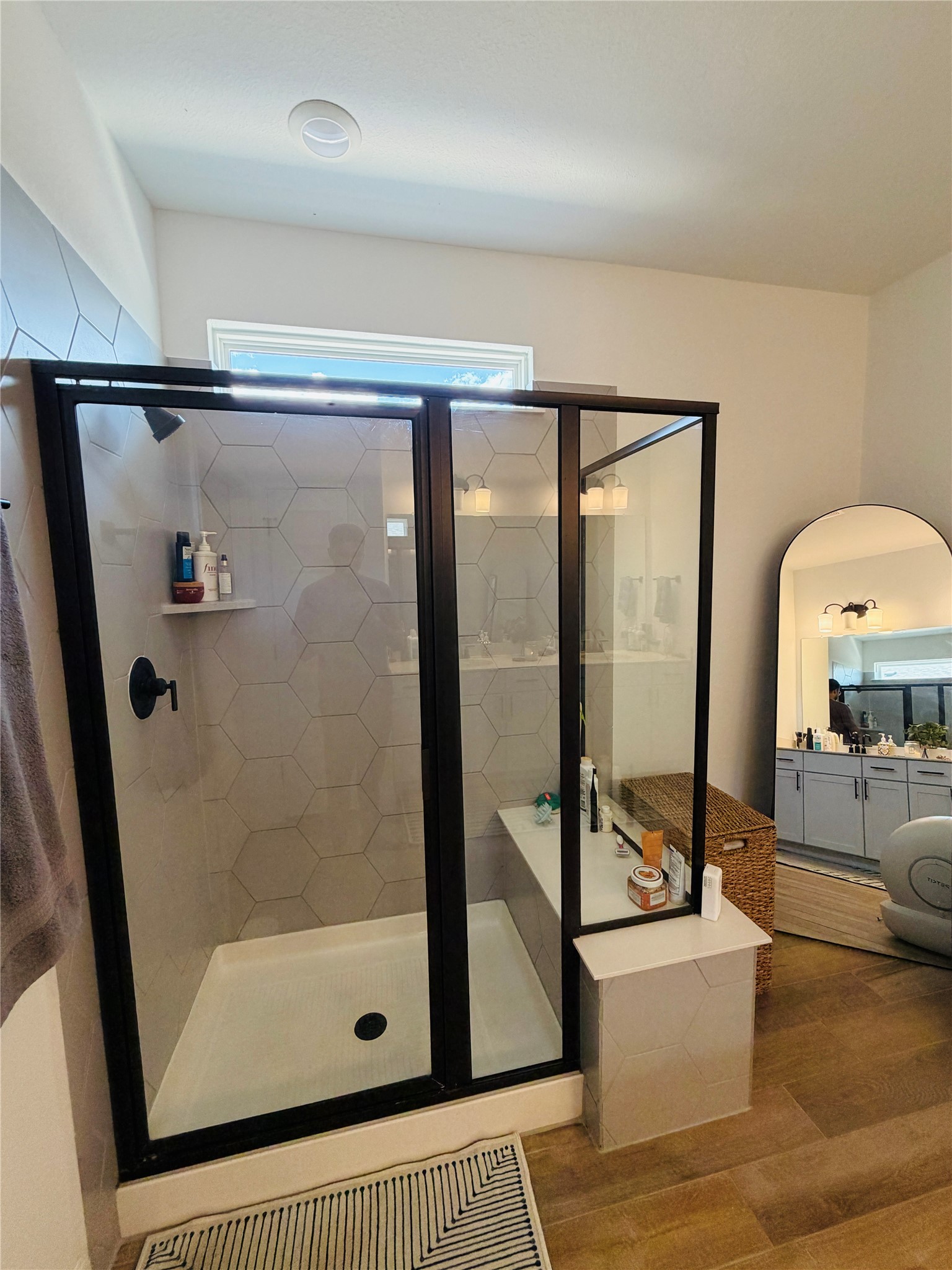 268 Fish Trap Road Dripping Springs, TX 78620 - Photo 14 of 23 A modern walk-in shower features black-framed glass panels, geometric tiling, and warm wood-look flooring.