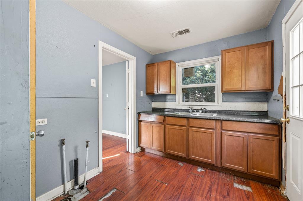 2225 Mitchell Avenue Waco, TX 76708 - Photo 6 of 16 Kitchen featuring wood-finish flooring, wood cabinetry, a double-basin sink, a window, and a white exterior door