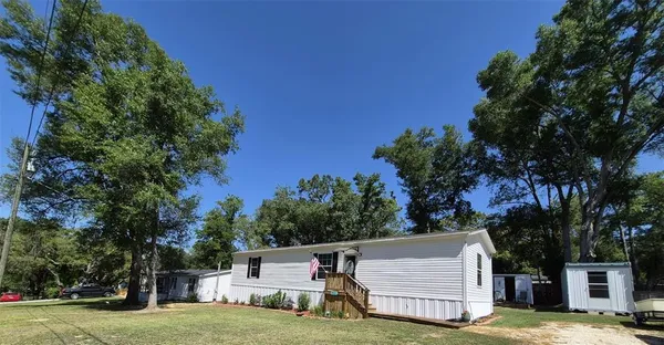 a view of a house with a big yard and large trees