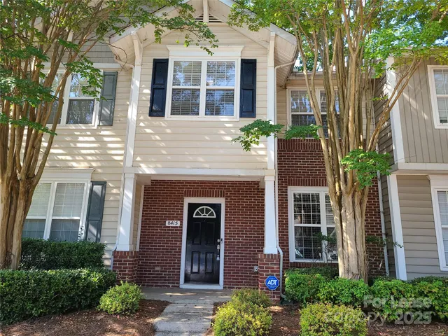 front view of a brick house with a large windows and a large tree