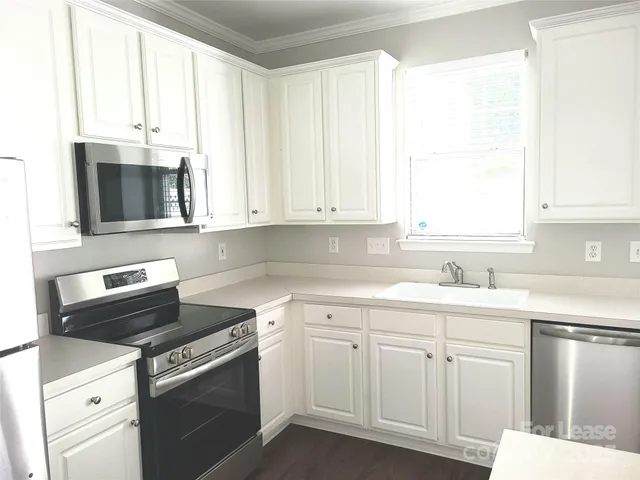 a kitchen with cabinets appliances a sink and a window