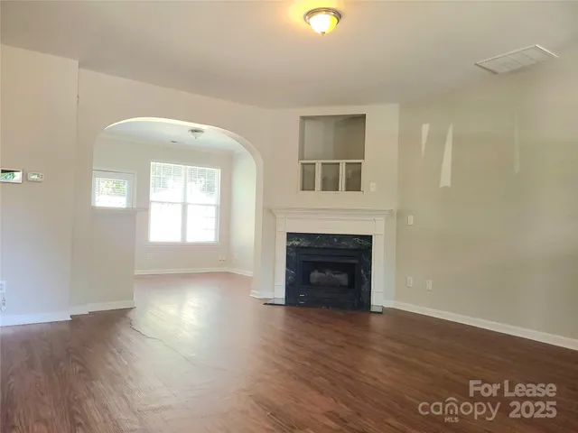 an empty room with wooden floor a fireplace and windows